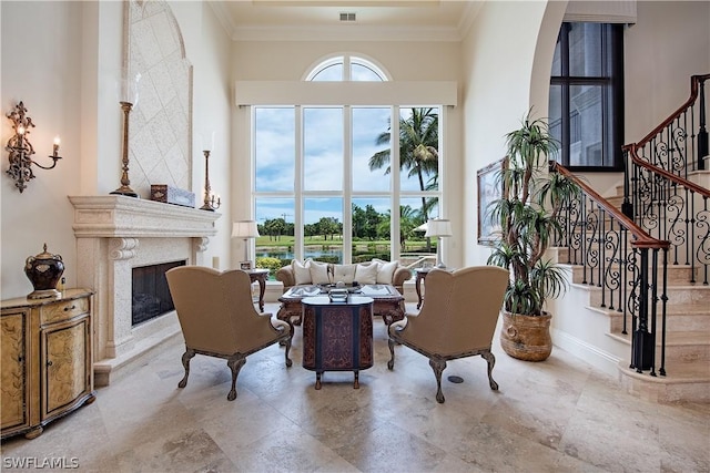 interior space featuring a towering ceiling, ornamental molding, and a premium fireplace