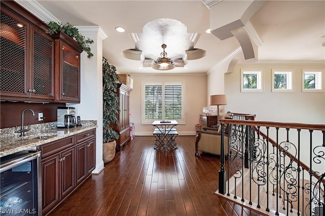 interior space featuring dark wood-type flooring, crown molding, sink, wine cooler, and light stone countertops