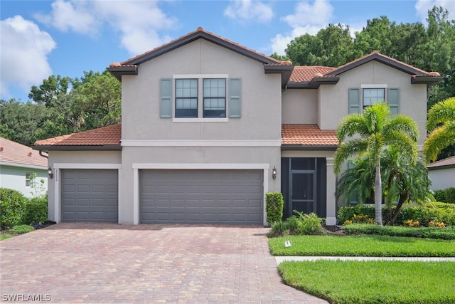 view of front of home featuring a garage, decorative driveway, a tile roof, and stucco siding