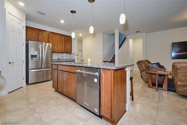 kitchen with pendant lighting, an island with sink, appliances with stainless steel finishes, and tasteful backsplash