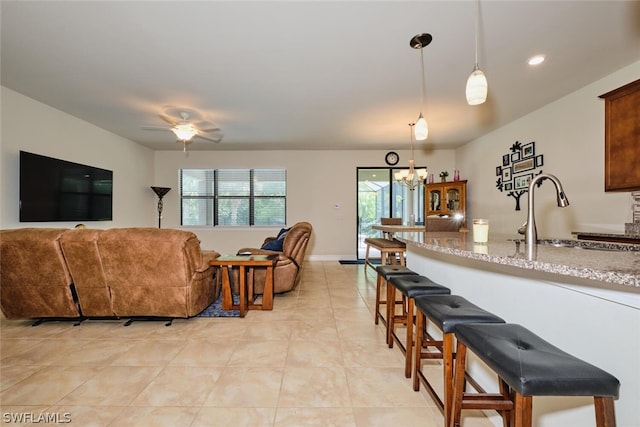 tiled living room with ceiling fan with notable chandelier and sink