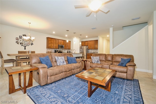 tiled living room with ceiling fan with notable chandelier