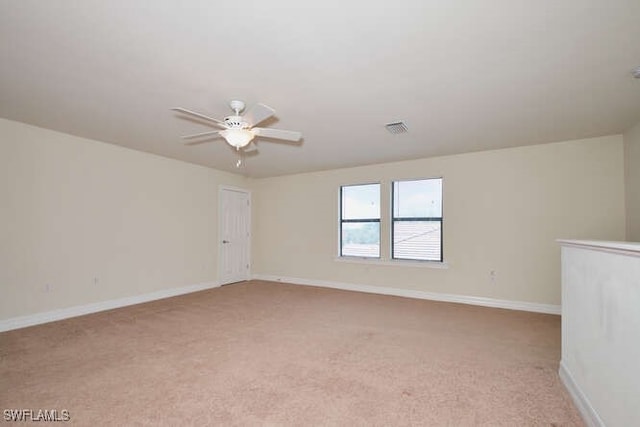 unfurnished room with a ceiling fan, visible vents, light carpet, and baseboards