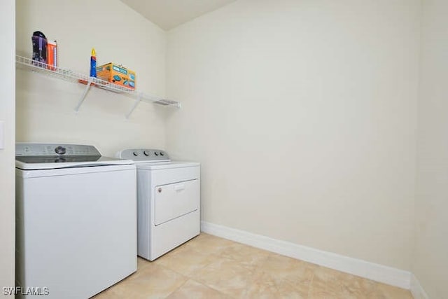 washroom featuring laundry area, washing machine and dryer, and baseboards