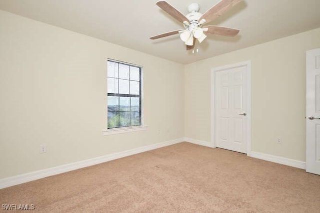 empty room with a ceiling fan, light carpet, and baseboards