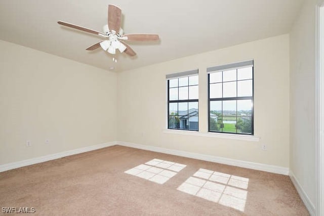 empty room featuring light carpet, a ceiling fan, and baseboards