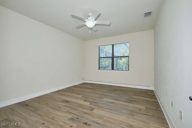unfurnished room with a ceiling fan, wood finished floors, visible vents, and baseboards
