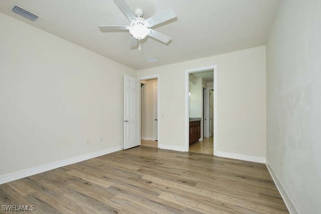 unfurnished room with a ceiling fan, visible vents, baseboards, and wood finished floors