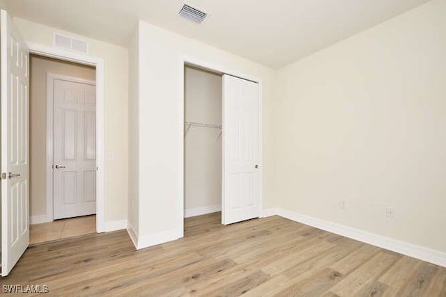 unfurnished bedroom featuring light wood finished floors, a closet, visible vents, and baseboards