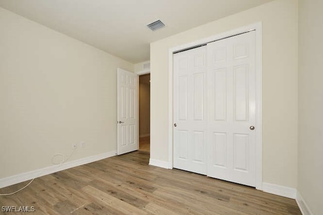 unfurnished bedroom featuring light wood finished floors, a closet, visible vents, and baseboards