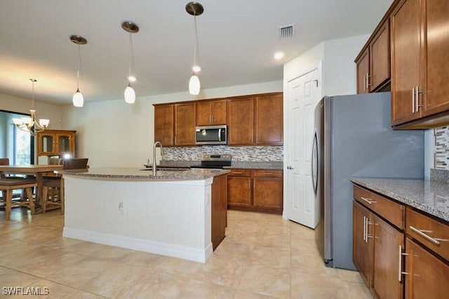 kitchen featuring appliances with stainless steel finishes, brown cabinetry, stone counters, and pendant lighting