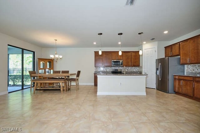 kitchen with a center island with sink, visible vents, appliances with stainless steel finishes, brown cabinets, and decorative light fixtures
