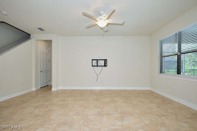 empty room featuring ceiling fan, visible vents, and baseboards