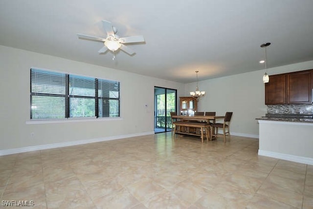 dining space featuring baseboards and ceiling fan with notable chandelier