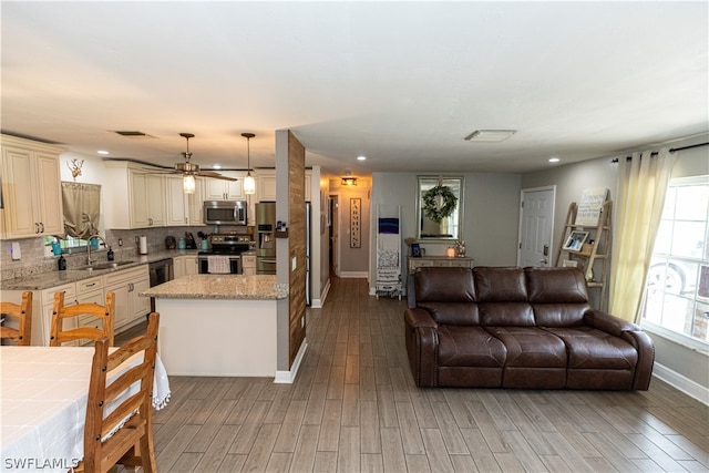 living room with a healthy amount of sunlight, sink, light hardwood / wood-style floors, and ceiling fan