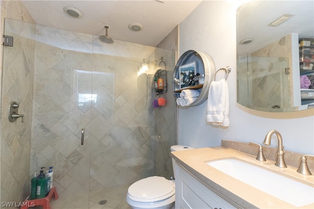 bathroom featuring a shower with shower door, vanity, and toilet