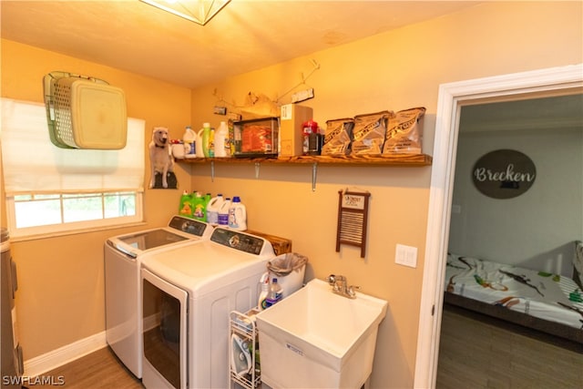 laundry room featuring washing machine and dryer, sink, and hardwood / wood-style floors