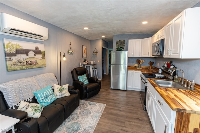 kitchen with wood counters, a wall unit AC, dark hardwood / wood-style flooring, stainless steel appliances, and sink