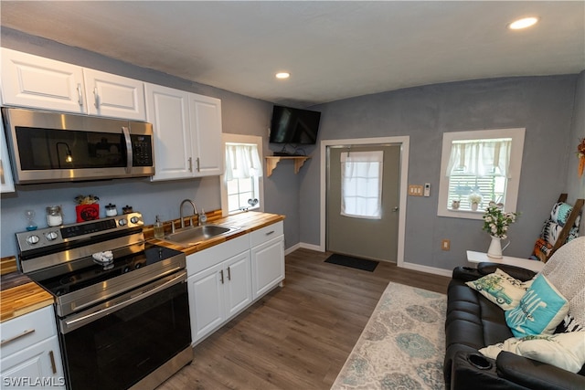 kitchen with butcher block counters, dark hardwood / wood-style flooring, appliances with stainless steel finishes, white cabinets, and sink