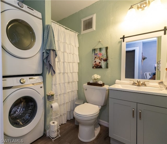 bathroom with stacked washer / drying machine, hardwood / wood-style floors, oversized vanity, and toilet