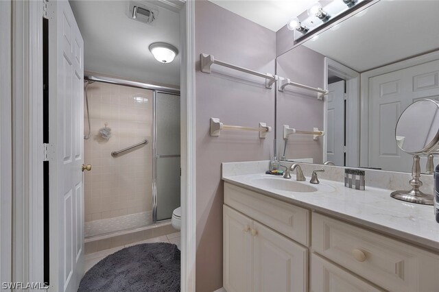 bathroom featuring tile patterned floors, vanity, toilet, and a shower with shower door