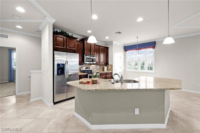 kitchen with light stone countertops, stainless steel appliances, sink, pendant lighting, and an island with sink