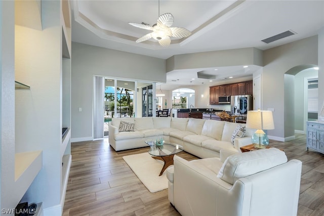 living room with a raised ceiling and ceiling fan