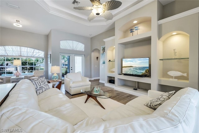 living room featuring french doors, ceiling fan, built in shelves, ornamental molding, and light hardwood / wood-style floors