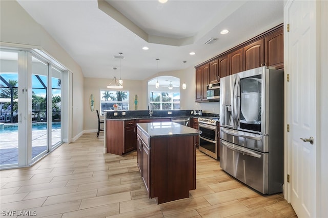 kitchen with sink, kitchen peninsula, pendant lighting, a kitchen island, and appliances with stainless steel finishes