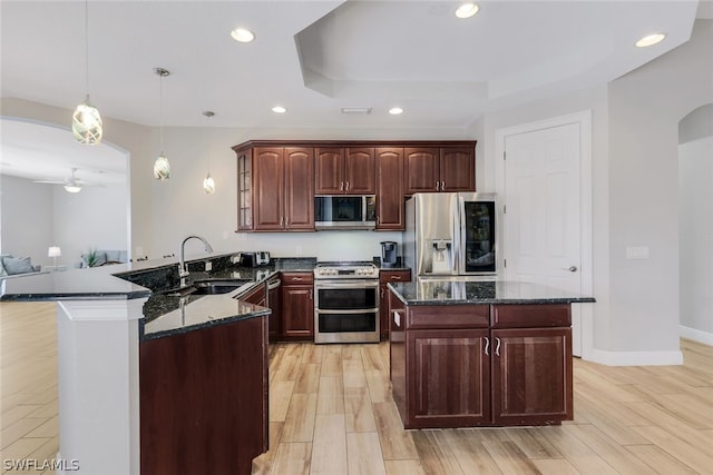 kitchen featuring kitchen peninsula, appliances with stainless steel finishes, ceiling fan, sink, and decorative light fixtures