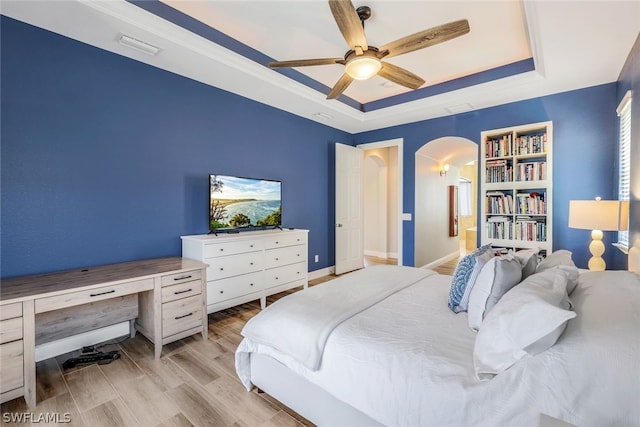 bedroom with a tray ceiling, light hardwood / wood-style flooring, and ceiling fan