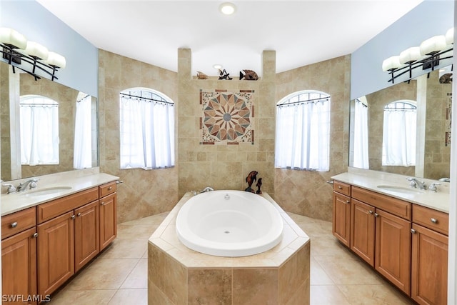 bathroom with tile patterned flooring, vanity, tiled bath, and tile walls