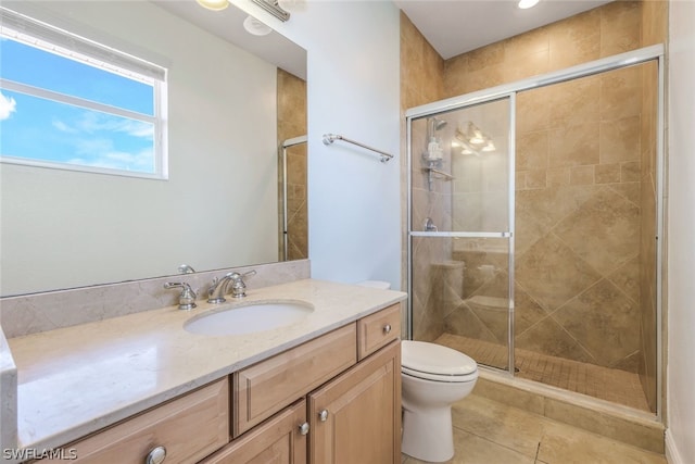 bathroom with tile patterned floors, vanity, toilet, and a shower with shower door