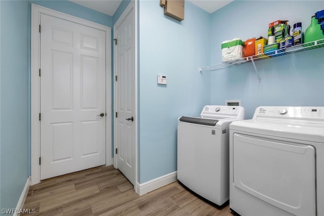 laundry room with washer and dryer and light wood-type flooring