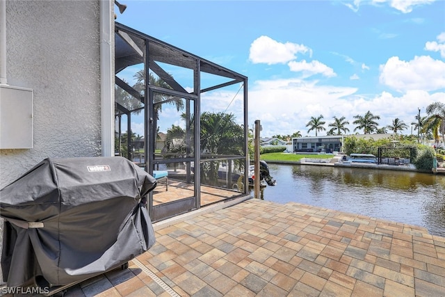 view of patio / terrace with a lanai, a water view, and grilling area