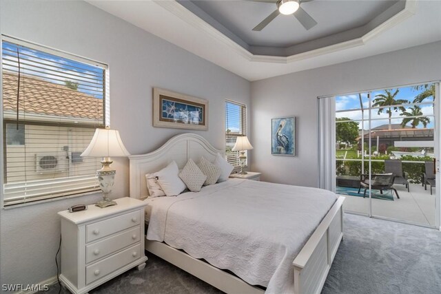 carpeted bedroom featuring ceiling fan, a raised ceiling, and multiple windows