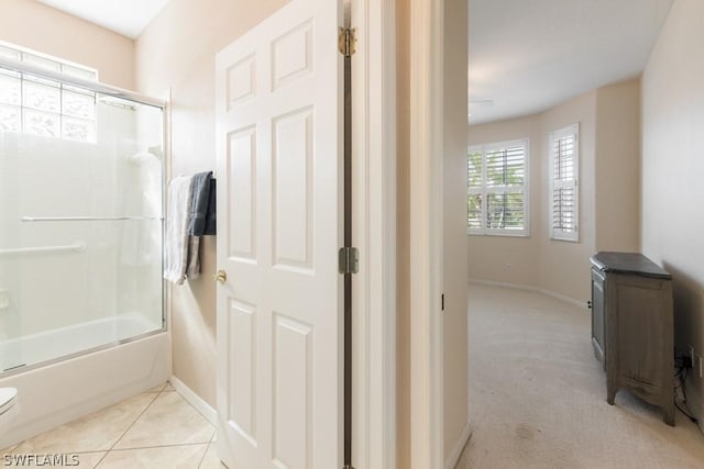 bathroom featuring tile patterned flooring, toilet, and bath / shower combo with glass door