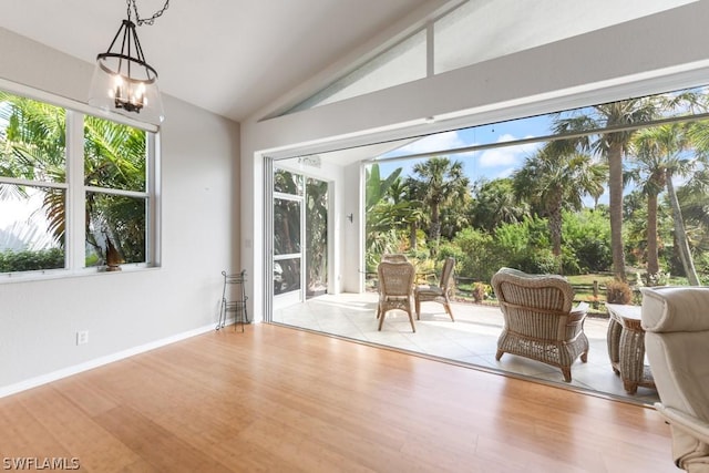 unfurnished sunroom with vaulted ceiling, a wealth of natural light, and a notable chandelier