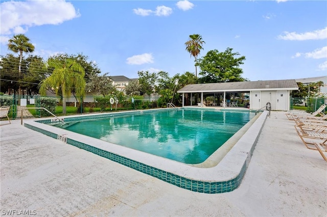 pool with a patio area and fence