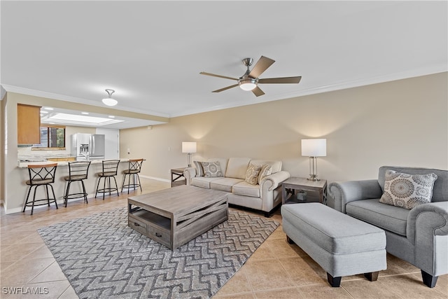 living room featuring light tile patterned flooring, ornamental molding, a skylight, and ceiling fan