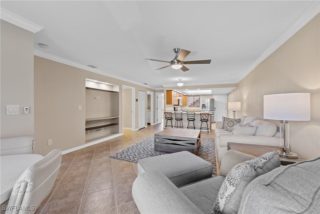 living room with baseboards, a ceiling fan, light tile patterned flooring, and crown molding
