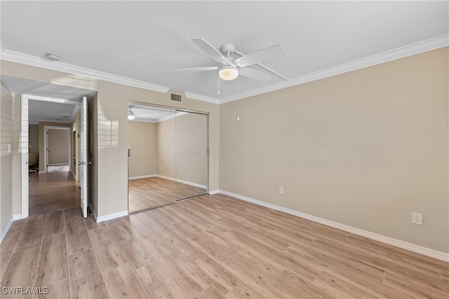 unfurnished bedroom featuring a closet, light wood finished floors, baseboards, ornamental molding, and visible vents