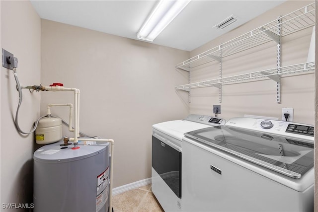 laundry area featuring washer and clothes dryer, light tile patterned flooring, electric water heater, baseboards, and laundry area