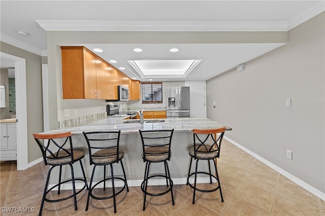 kitchen featuring sink, kitchen peninsula, stainless steel appliances, a breakfast bar area, and crown molding