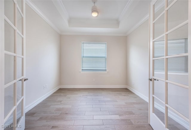 empty room with french doors, a tray ceiling, and light hardwood / wood-style floors