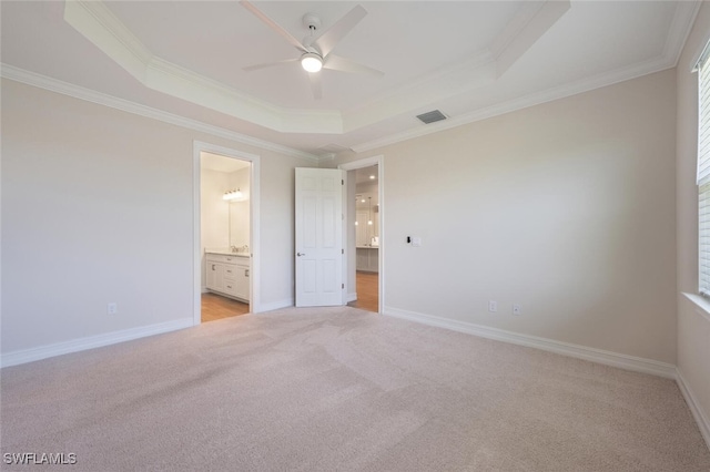 unfurnished bedroom featuring ceiling fan, a raised ceiling, light colored carpet, and ensuite bath