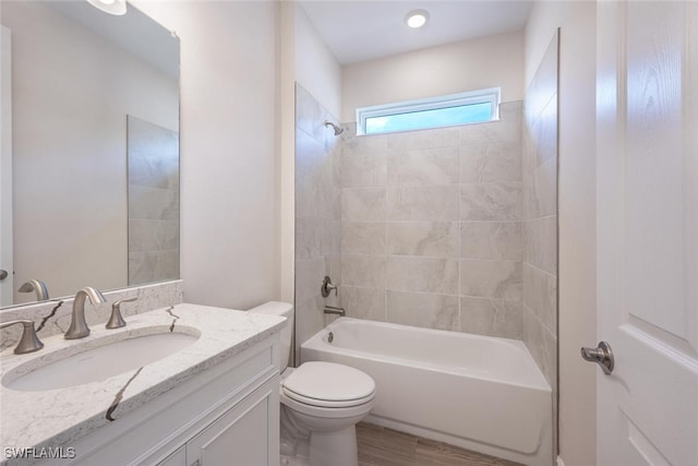 full bathroom with vanity, wood-type flooring, tiled shower / bath combo, and toilet