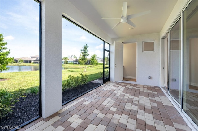 unfurnished sunroom with a water view, ceiling fan, and a healthy amount of sunlight