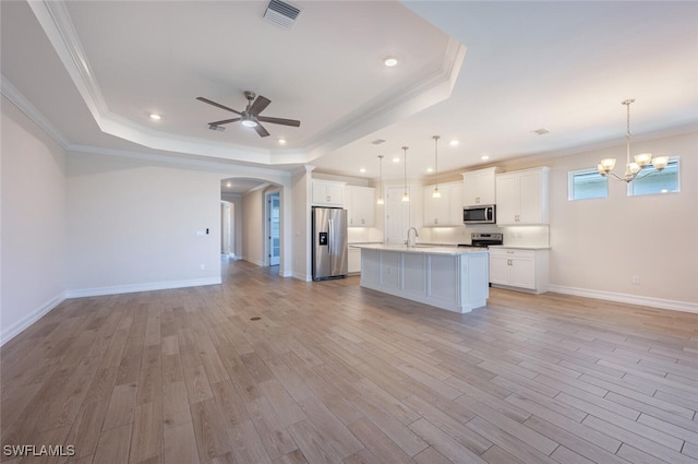 kitchen featuring white cabinets, pendant lighting, stainless steel appliances, and a tray ceiling