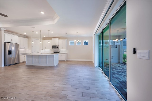 kitchen with white cabinetry, a notable chandelier, decorative light fixtures, a kitchen island with sink, and appliances with stainless steel finishes